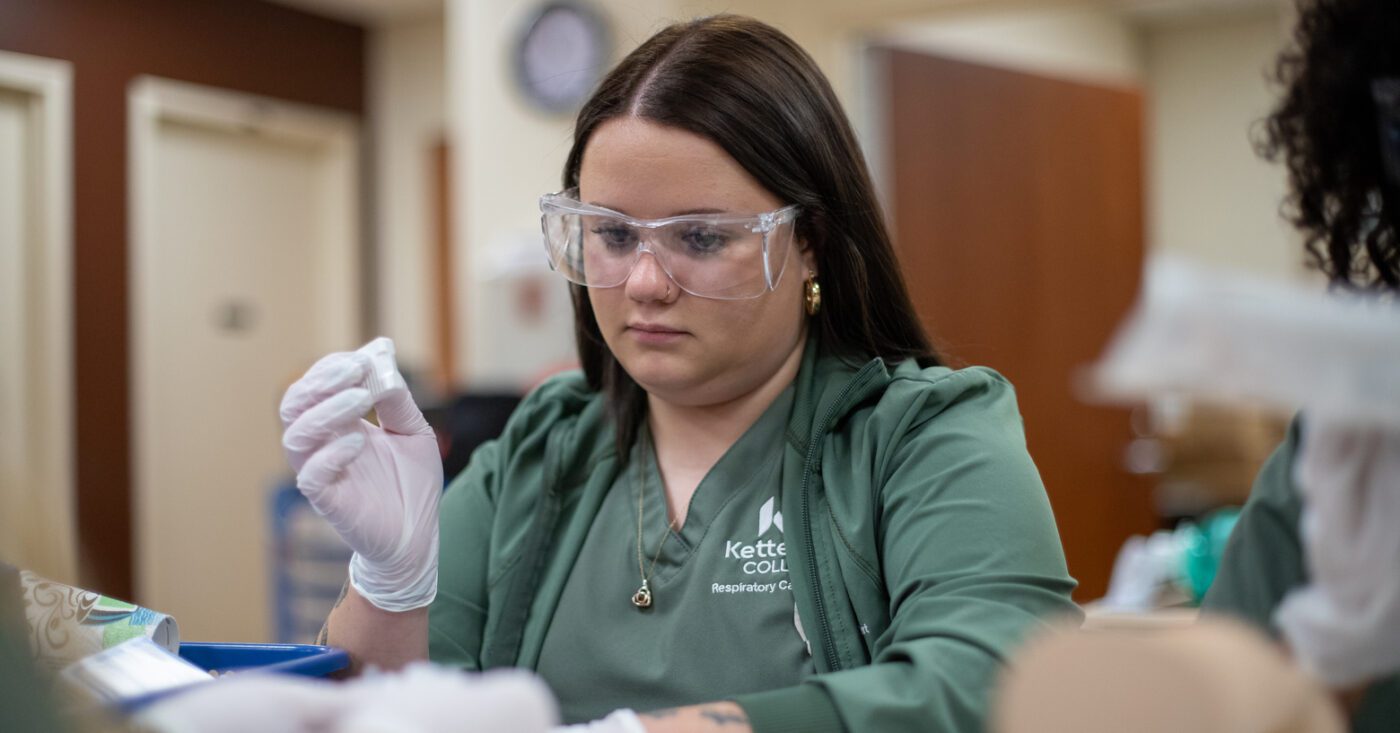 A Respiratory Care student at Kettering College works on an infant mannequin during a lab.