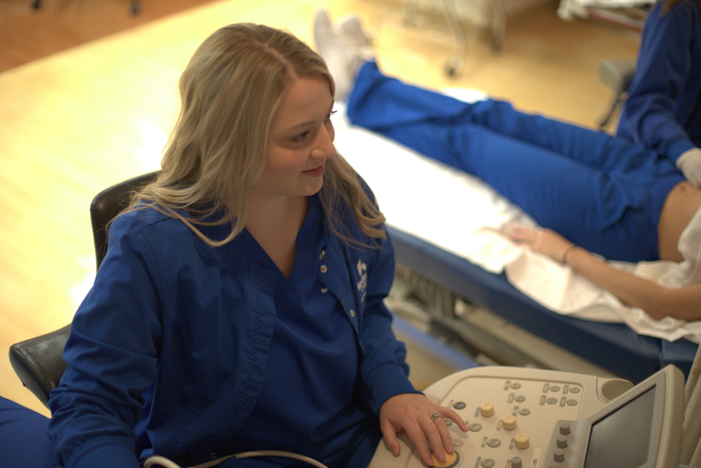 A student in the Kettering College Sonography program works in a lab with her peers on an ultrasound machine.